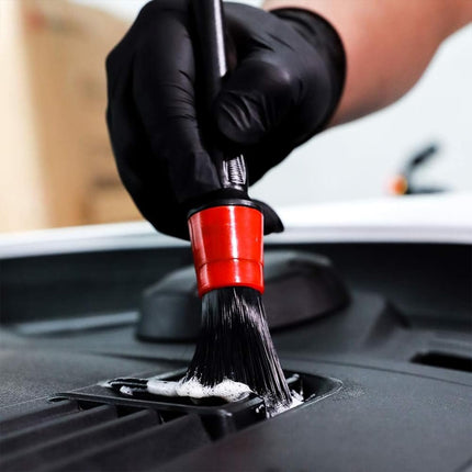 Person cleaning a car's engine bay with a brush