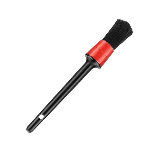 Cleaning brush with black bristles and a red handle on a white background