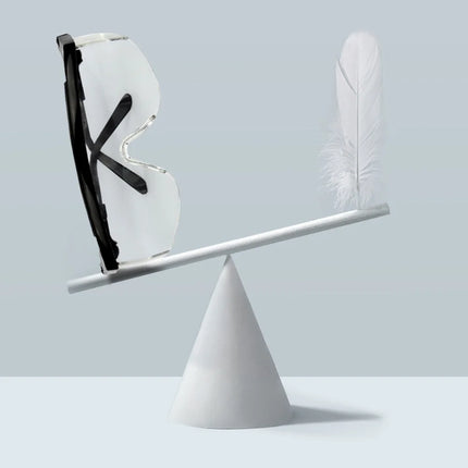 Balancing scale with a shoe and a feather on a light gray background